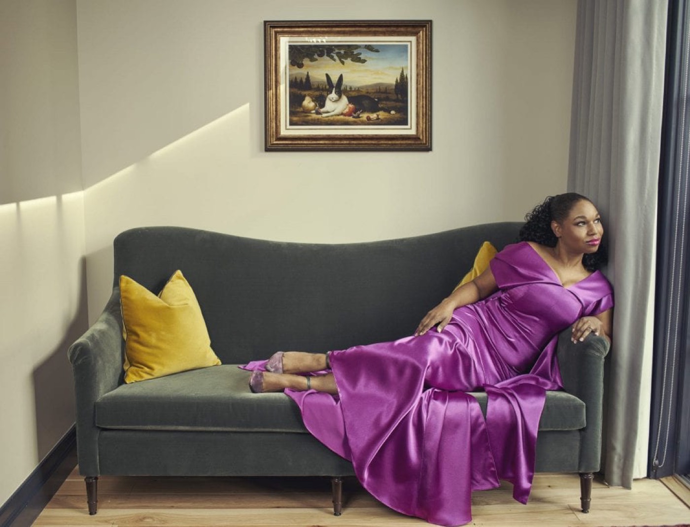Stephanie in a violet gown on a velvet sofa