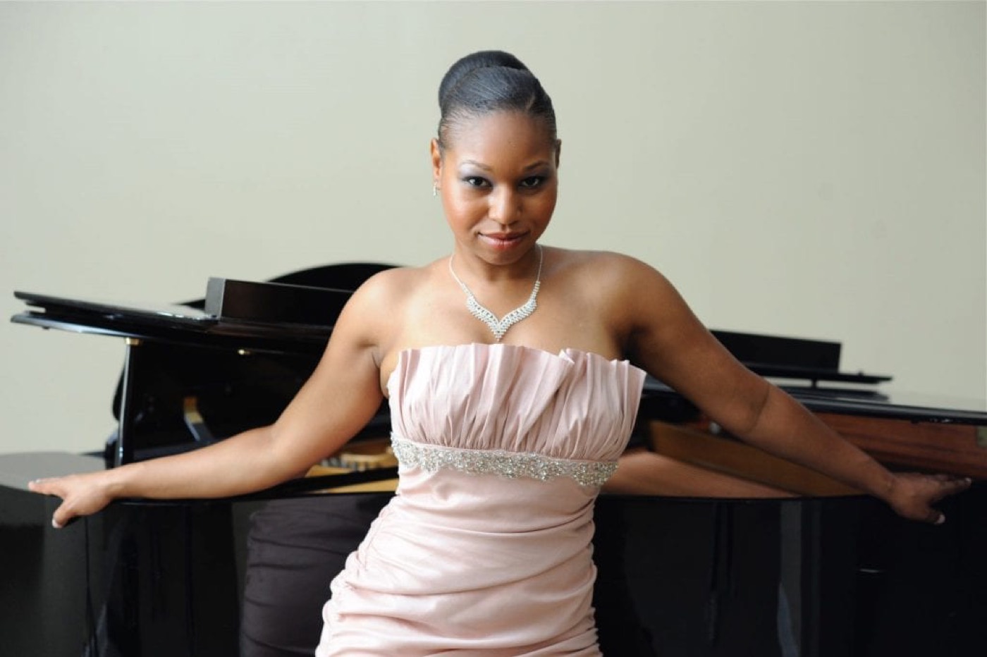 Stephanie at a grand piano in a blush gown